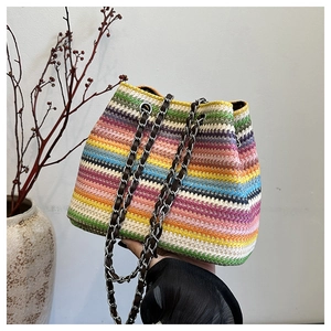 Close-up of colorful striped woven bucket bag with elegant metal chain shoulder strap