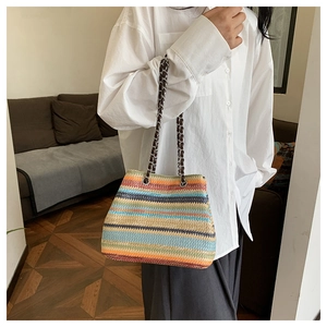 Detail of colorful hand-woven tote bag with vibrant stripes and leather metal chain strap