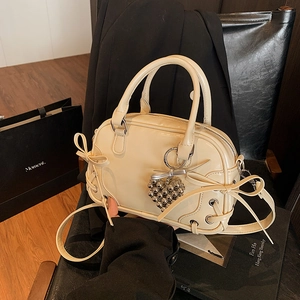 Sac Boston crème avec nœuds élégants, breloque cœur et bandoulière amovible
