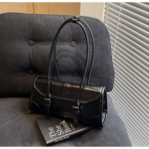 Detailed view of black glossy leather handbag on a corduroy chair with soft shadows
