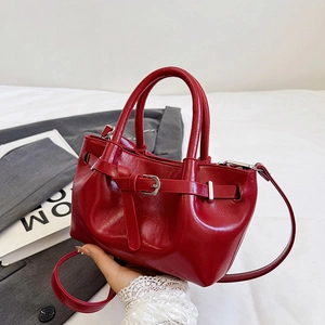 Glossy red patent leather handbag with silver buckle straps and adjustable shoulder strap