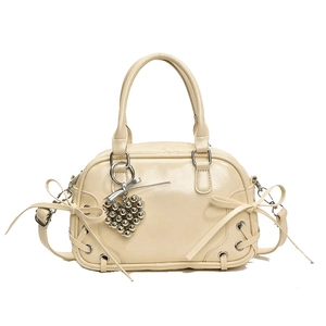 Sac Boston crème avec nœud décoratif, breloque cœur et lacets croisés sur fond blanc
