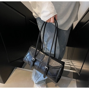 Detail of glossy black leather tote bag with buckle straps shown in a lifestyle setting