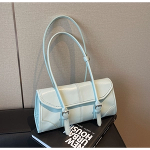 Detail of light blue patent leather baguette bag resting on books with silver buckles