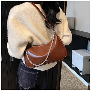 Brown hobo shoulder bag with silver chain detail shown on a model in a casual setting