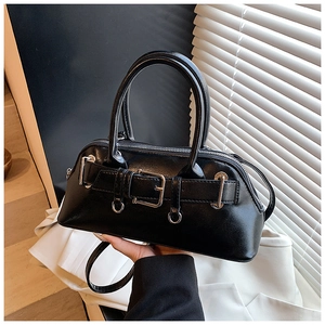 Détail d'un sac à main noir montrant la texture du cuir, les boucles et la bandoulière