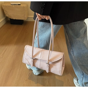 Detail of light pink shoulder bag featuring a sleek flap closure and decorative buckle strap
