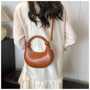 Detail der karamellbraunen Mondsichel-Tasche mit geknotetem Griff und mattem Finish