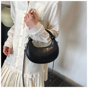 Detail einer schwarzen Halbmond-Tasche mit rundem Kugelgriff und verstellbarem Tragegurt