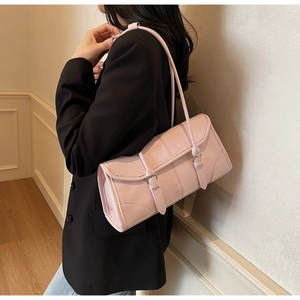 Close-up of pink crossbody bag with parallel buckle straps on black blazer outfit