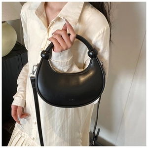 Detail der schwarzen Hobo-Tasche mit Knotenelementen und verstellbarem Riemen am Outfit