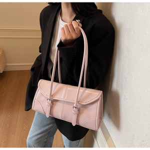 Detail view of a pale pink patent leather underarm bag featuring silver metal buckles