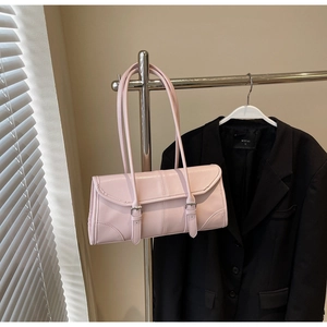 Detailed view of pink faux leather bag with vertical stitching and metal buckle on strap