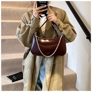 Detail of burgundy hobo bag with high-gloss finish and silver metal chain strap