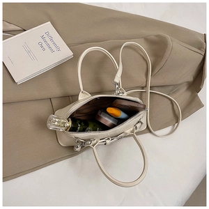 Détail de l'intérieur du sac beige montrant l'espace pour les cosmétiques et le parfum