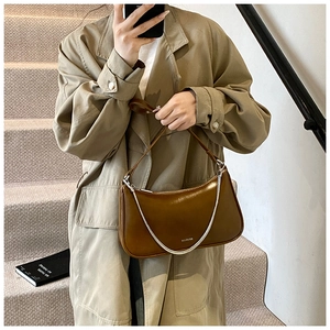 Brown glossy underarm bag with silver chain and NO FILTER text on khaki trench coat