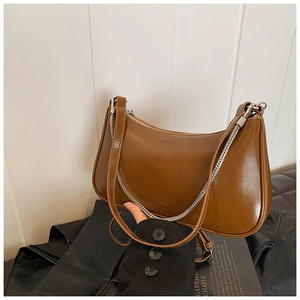 Detail of a brown leather hobo bag featuring adjustable strap and silver chain accent