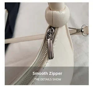 Detail of silver smooth zipper and knotted leather handle on off-white handbag