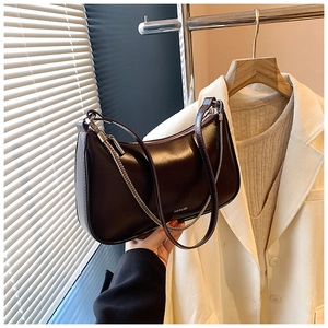Detail of dark brown leather underarm bag with NO FILTER text and metal chain strap