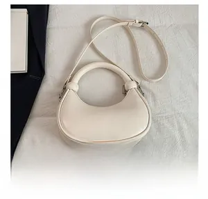 Detailed view of cream leather crescent bag with top handle and adjustable strap