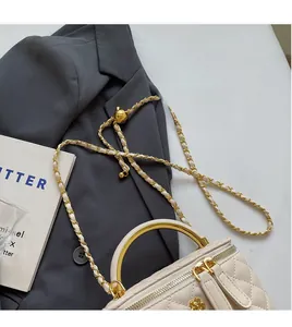 Close-up of cream quilted bucket bag with golden arch handle and chain strap on blazer