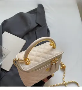 Close-up of quilted cream leather bag with gold metal handle and chain strap details