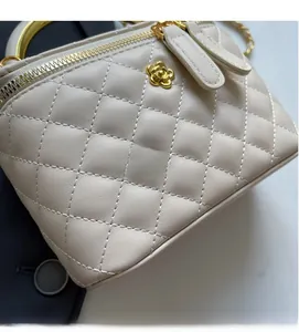 Detailed view of beige quilted bucket bag with gold flower zipper and chain strap