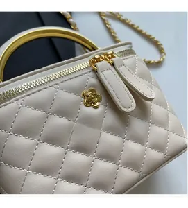 Close-up of beige quilted bucket bag with gold handle and camellia floral hardware