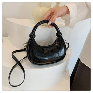 Detail of black pleated patent leather crescent bag with silver spherical hardware accents