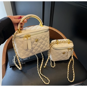 Close-up of quilted beige bucket bag with metal camellia detail and chain strap