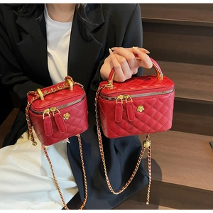 Detail of red quilted bucket bags with golden camellia ornaments and chain straps