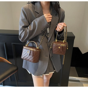 Close-up of brown quilted leather bucket bags with gold chain and floral zipper detail