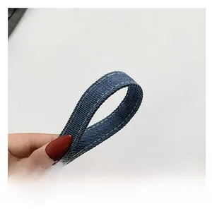 Gros plan sur la bandoulière en denim bleu avec double surpiqûre blanche contrastée