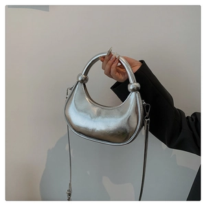 Detail of silver crescent handbag with metallic finish and sphere handle accents