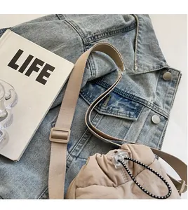 Detail view of beige canvas bucket bag with adjustable strap and drawstring closure