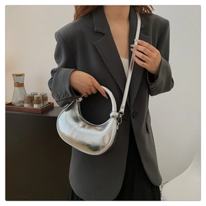 Close-up of a silver crescent-shaped handbag with a stylish round metal handle