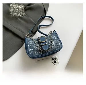 Detalle del bolso de hombro en denim azul con pedrería plateada y cadena metálica