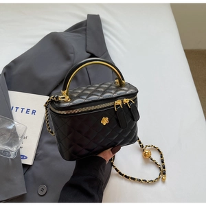 Close-up of black quilted bucket bag with gold camellia hardware and chain handle