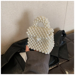 Vue détaillée d'un sac à main artisanal en perles blanches avec tissage et poignée ronde