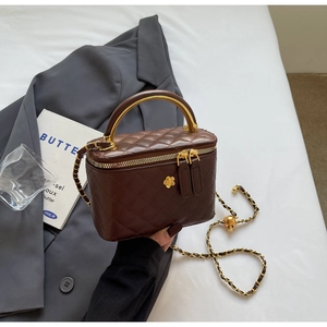 Detail of dark brown quilted bucket bag with golden camellia and metal top handle