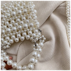 Detailed close-up of handmade white pearl woven bag with silver metal ring buckle