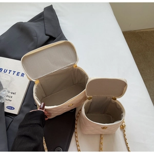 Detailed view of beige quilted leather bucket bags with camellia clasps and chain straps