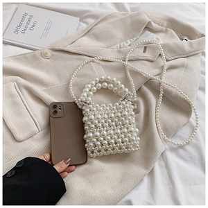 Macro detail of hand-woven pearl shoulder bag with high-gloss beads and chain strap