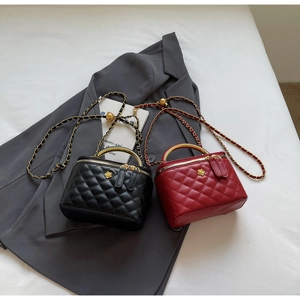 Close-up of quilted bucket bags with gold flower emblem and chain strap on grey blazer