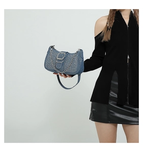 Détail du sac baguette en jean bleu avec strass, boucle argentée et bandoulière chaîne
