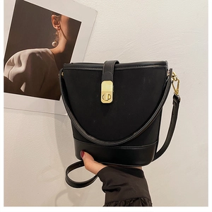 Detail of black bucket bag featuring canvas leather patchwork and gold metal turn-lock