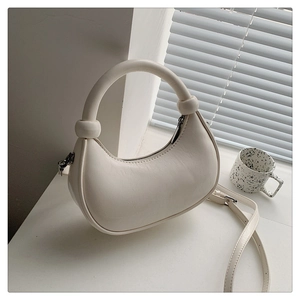 Detail of cream crescent bag with knotted handle decor and silver zipper in soft light