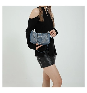 Détail du sac bandoulière en jean bleu clair avec rivets argentés et chaîne en métal