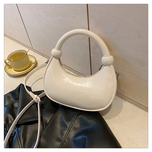 Detail of cream mini crescent handbag with curved handle and spherical knot decoration