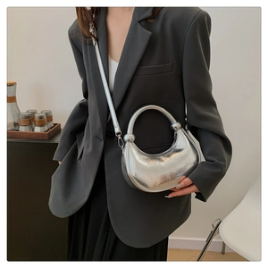 Close-up of a silver crescent moon bag with metallic finish and circular handle detail